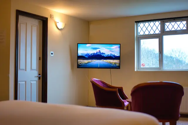 Royal Clifton Suite lounge corner with wall-mounted TV and velvet armchairs
